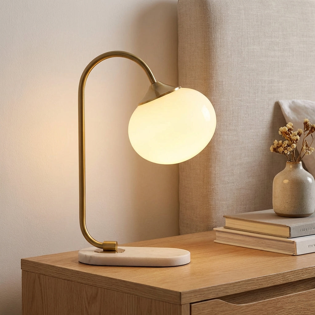 Lampa stołowa z zaokrąglonym szklanym kloszem i zakrzywionym metalowym trzonem