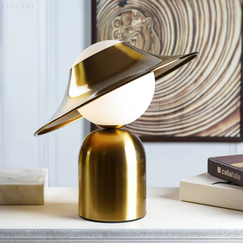 Elegancka metalowa lampa stołowa w złotym kolorze z odchyloną głowicą i ciepłym światłem