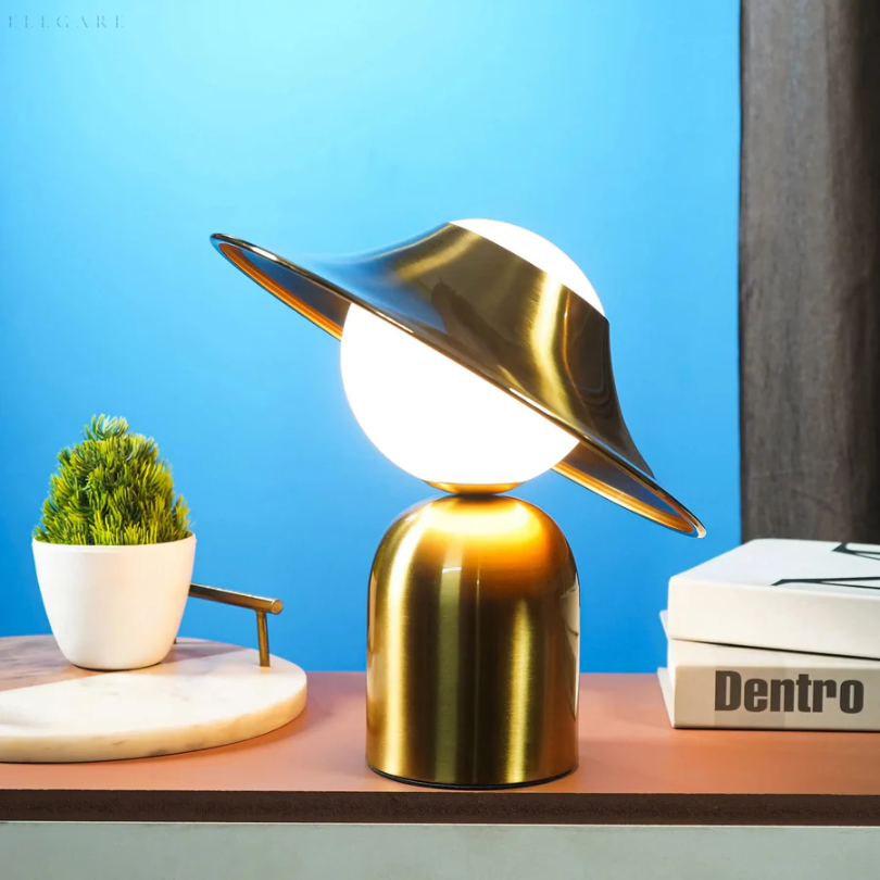 Elegancka metalowa lampa stołowa w złotym kolorze z odchyloną głowicą i ciepłym światłem