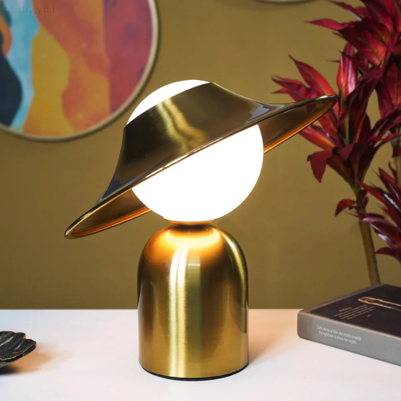 Elegancka metalowa lampa stołowa w złotym kolorze z odchyloną głowicą i ciepłym światłem